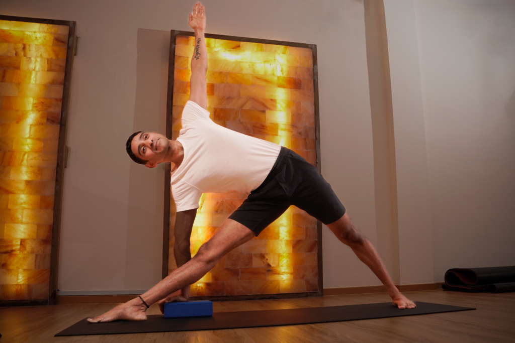 instructor in a salt heat Hatha1 class holding a gentle yoga pose in a heated studio